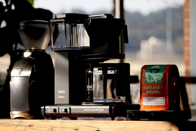 Technivorm Moccamaster KBG Coffee Maker in black next to a bag of Greater Good coffee, Clive Coffee - Lifestyle - large