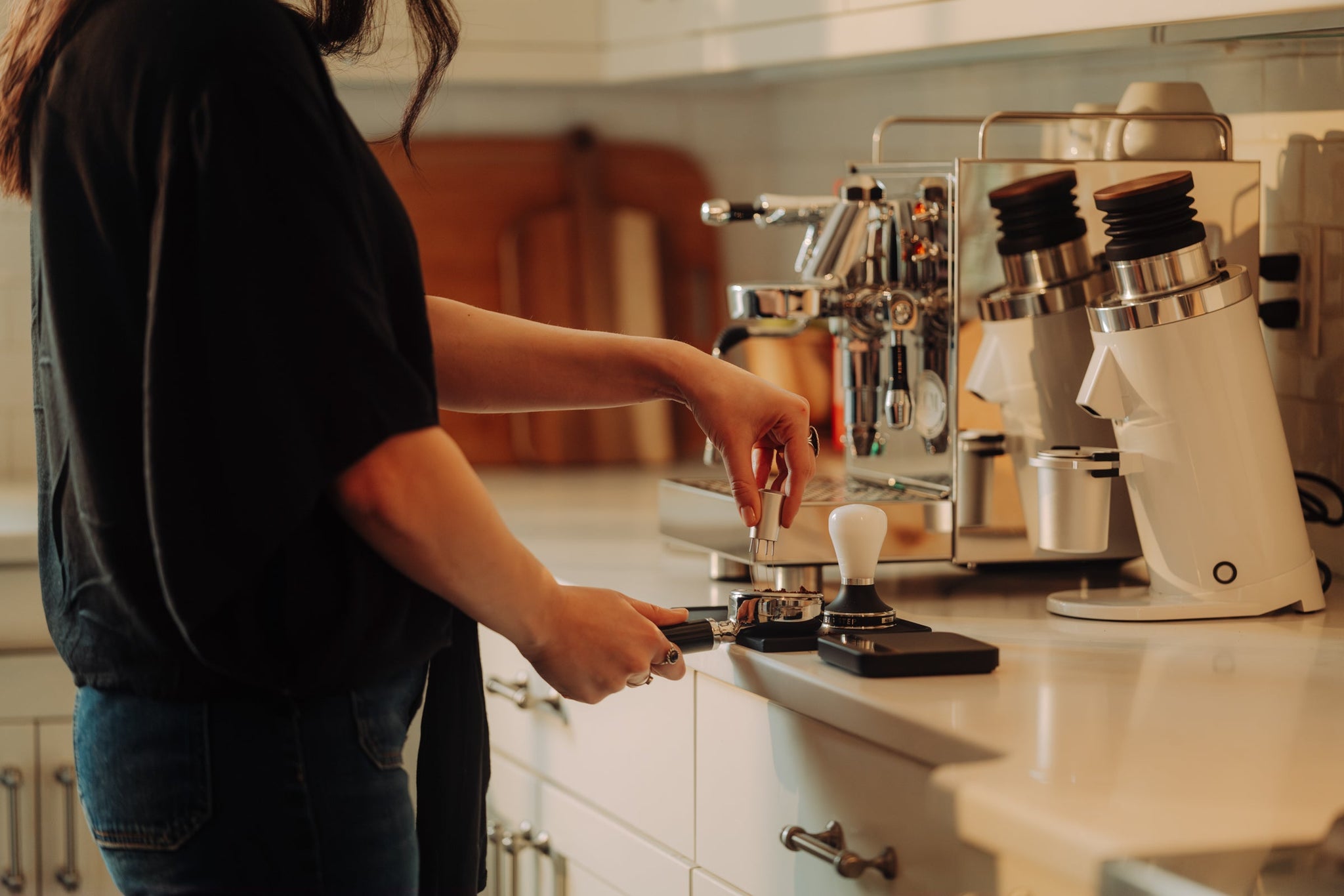 Barista using a distribution tool on a portafilter at a shiny chrome espresso machine