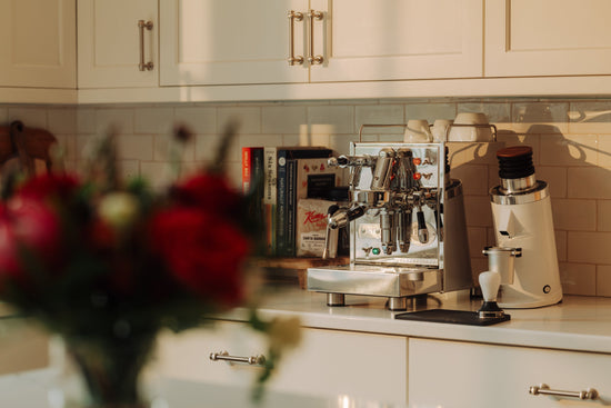 Professional espresso machine on a kitchen counter with a grinder and cookbooks nearby