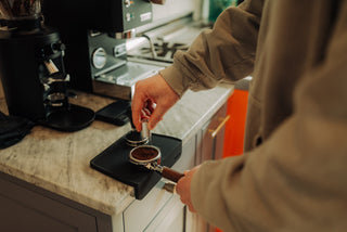 Close up of hands loading ground coffee into a portafilter on a home espresso machine