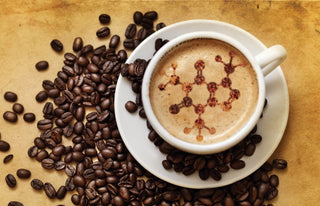 Overhead view of a white espresso cup with crema and a red decorative pattern on top, surrounded by roasted coffee beans.