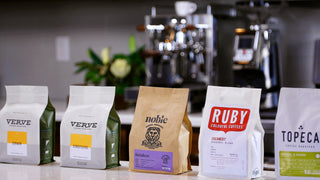 Assorted coffee bags arranged on a counter with Verve bags on the left and Ruby Colorful Coffees on the right