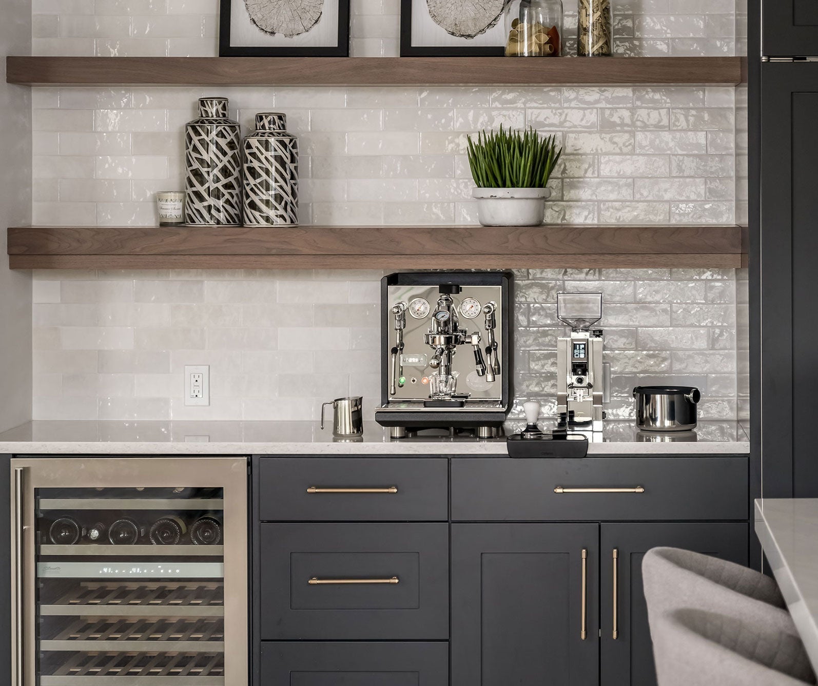 Modern kitchen coffee station with espresso machine, grinder, and scale on a white tiled backsplash with shelves