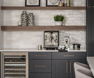 Modern kitchen coffee station with espresso machine, grinder, and scale on a white tiled backsplash with shelves
