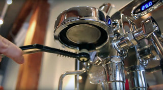 Close up of a chrome espresso machine with a pressure gauge visible on the right