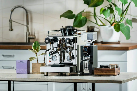 Espresso setup on a kitchen counter with a shiny machine a dose scale and stacked glasses ready for brewing