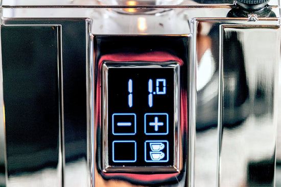 Close up of an espresso grinder control panel with a blue digital readout and plus minus buttons