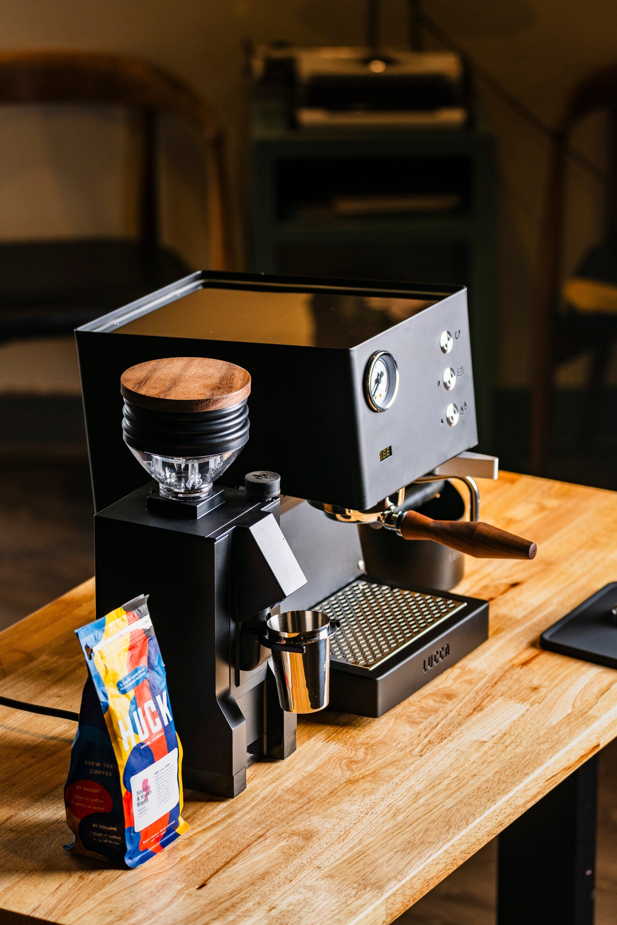 Espresso machine with a portafilter attached and a bag of coffee on a wooden counter.