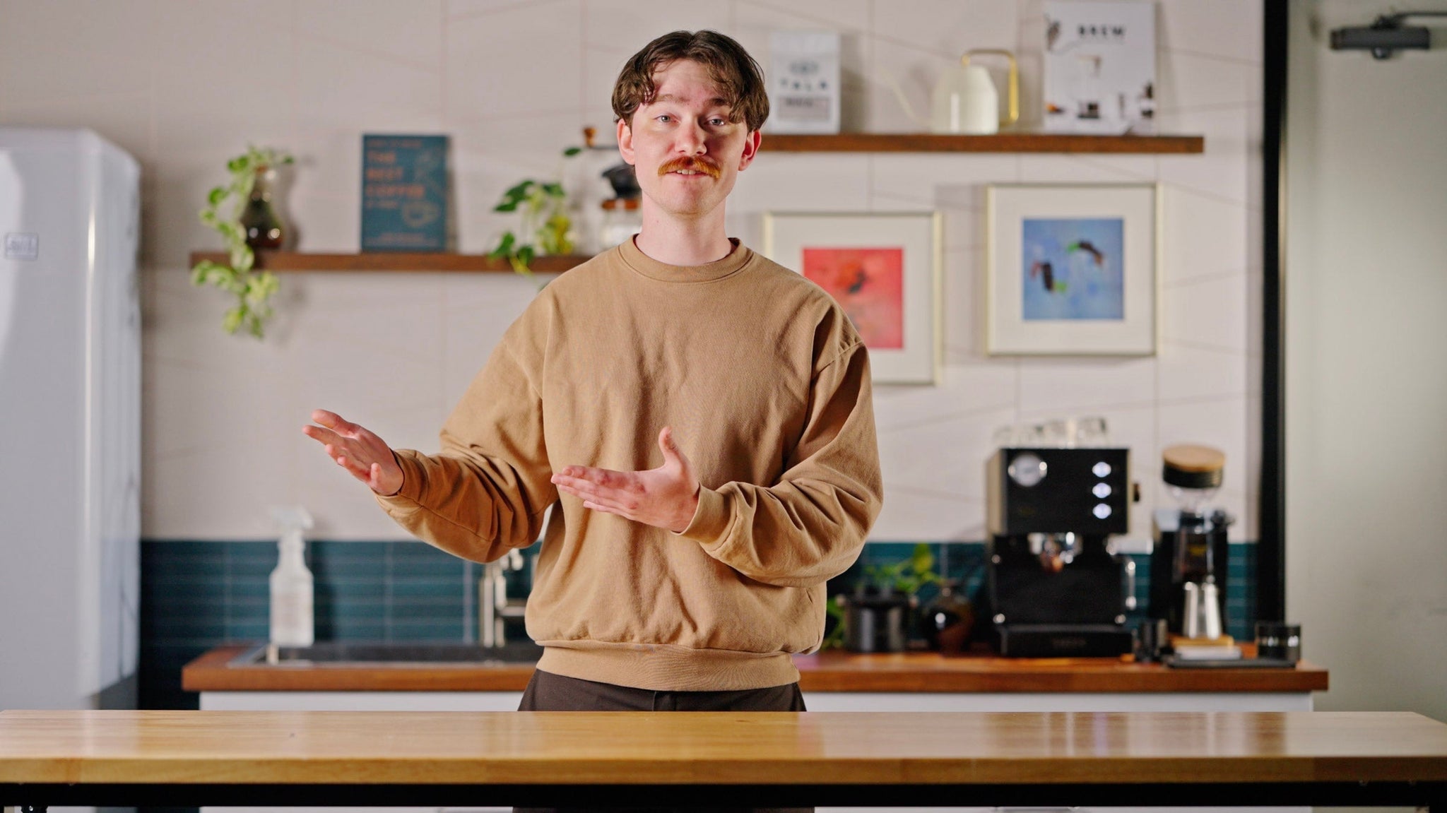 Talent with hands emphatically points to the left in front of an espresso machine lifestyle by Clive Coffee.