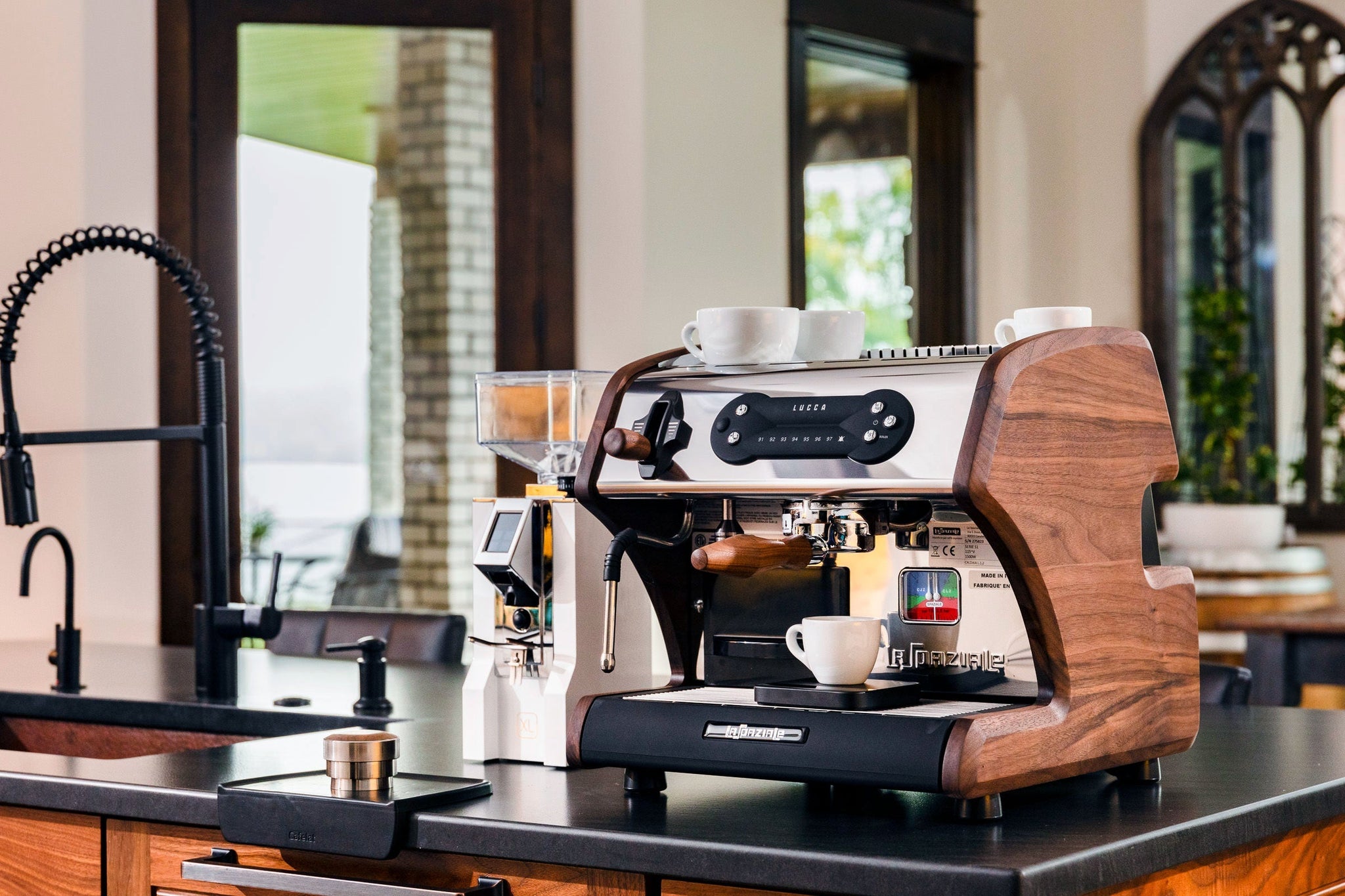 Espresso setup with a grinder on the right and two white cups resting on top of the machine.