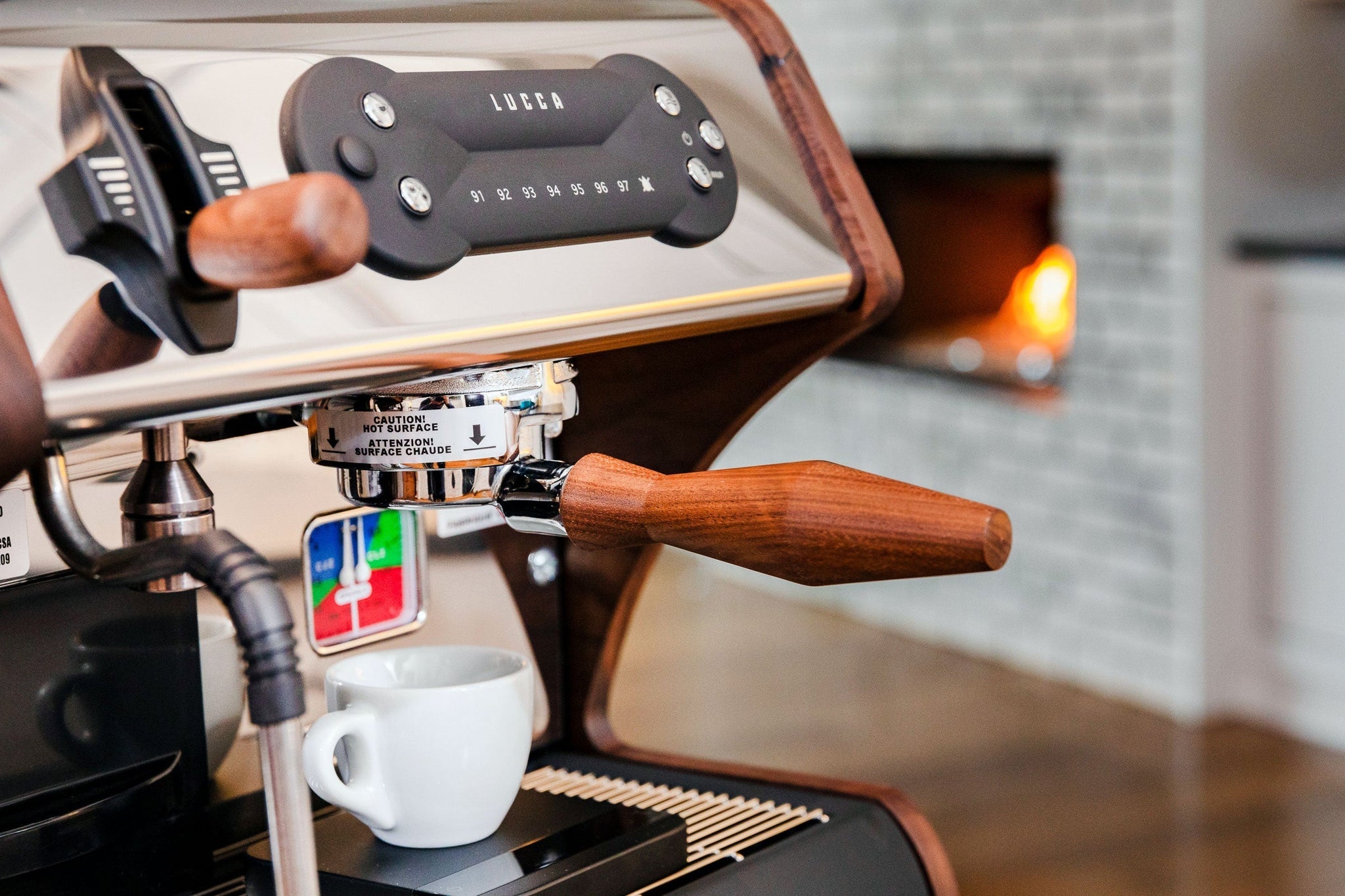 Close-up of a LUCCA espresso machine group head with a portafilter above a white cup