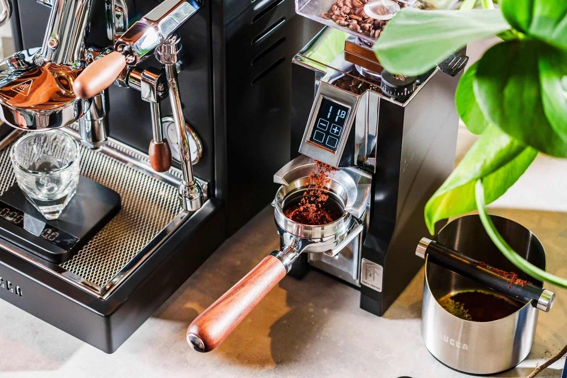 Close up of a polished espresso machine with a portafilter that has a wooden handle and ground coffee visible in the dosing area.
