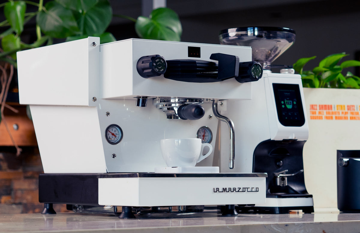 La Marzocco Linea Mini espresso machine in white with gauges and a portafilter on a polished counter