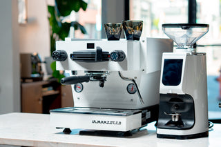 White La Marzocco espresso machine with dual portafilters and gauges on a cafe counter