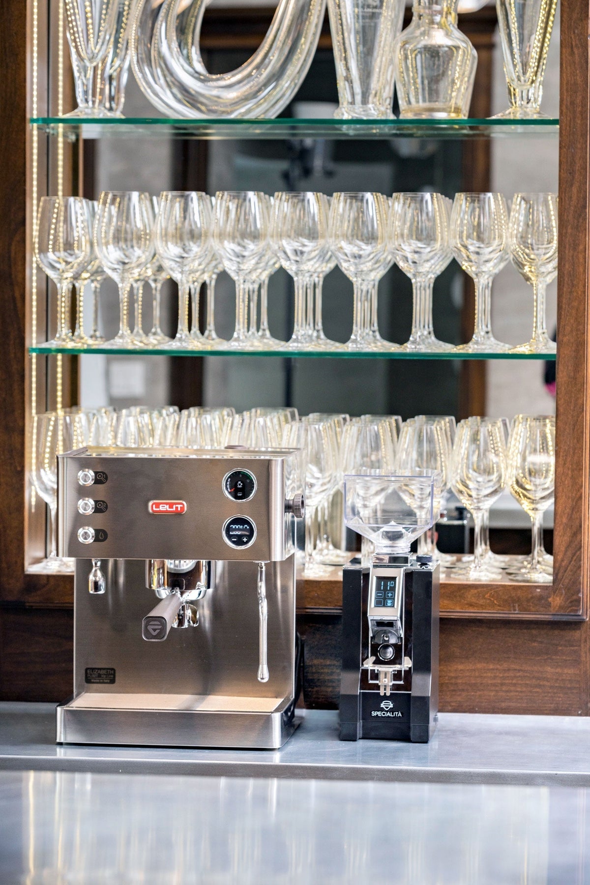 Lelit Elizabeth espresso machine on a counter with glassware arranged on open shelves behind.
