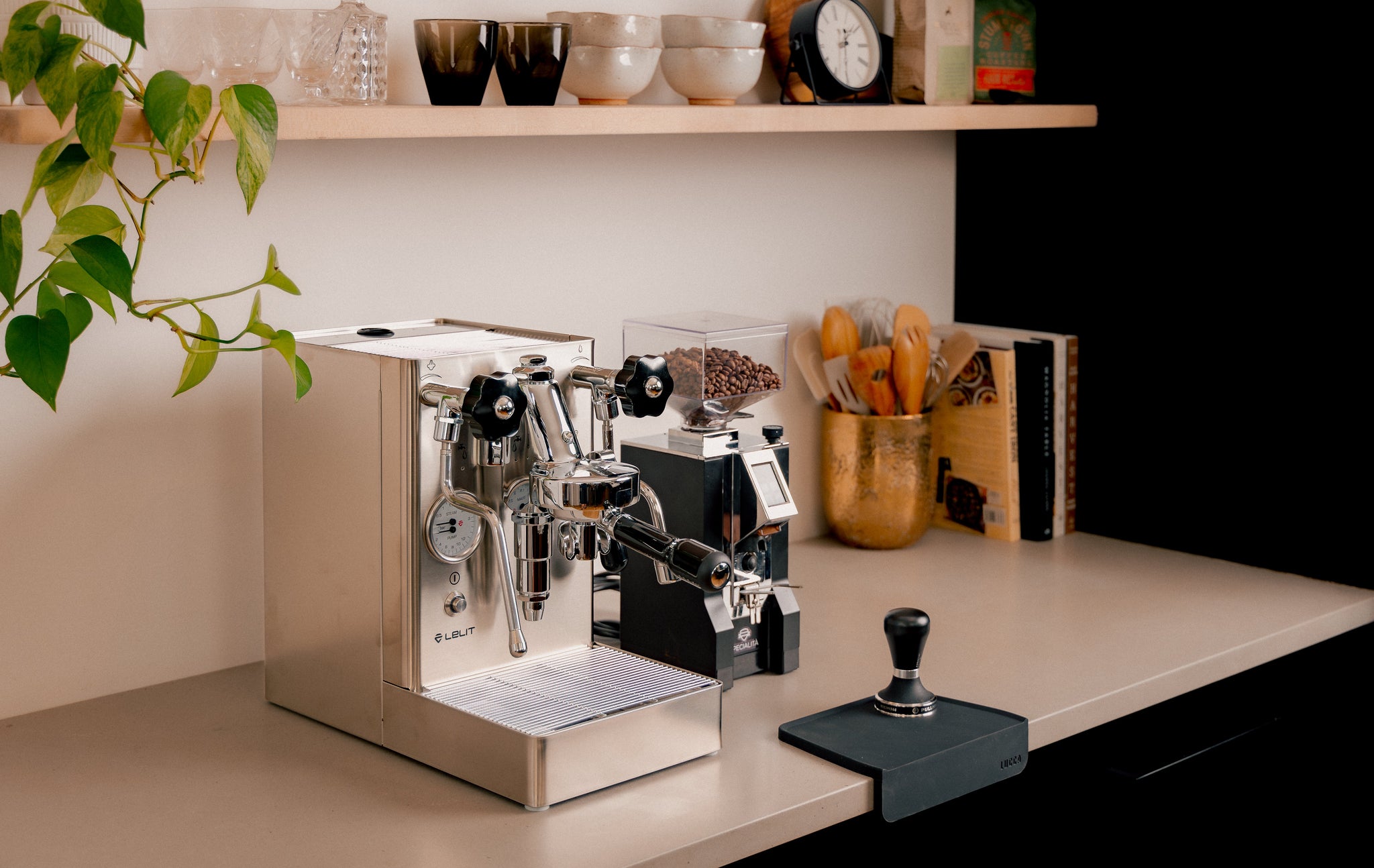 Compact home espresso setup with a black dual boiler machine on a wooden counter and a grinder nearby.