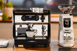 LUCCA espresso machine with portafilter beside a compact grinder on a wooden counter.