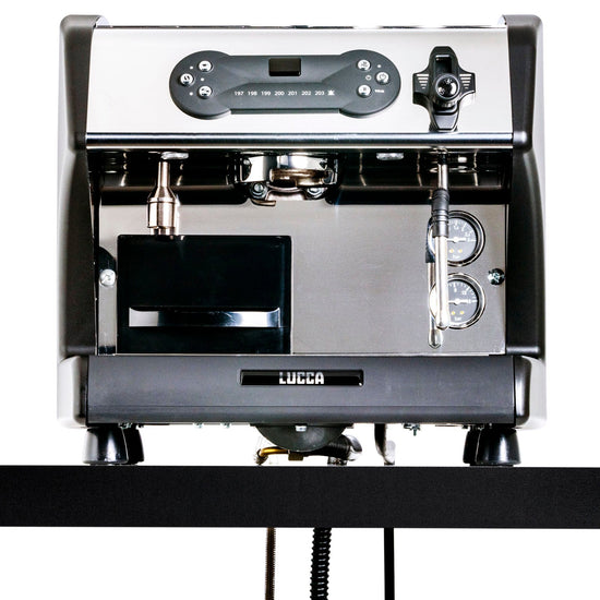 Front view of a LUCCA espresso machine with portafilter, steam wand, and two gauges on a chrome panel.