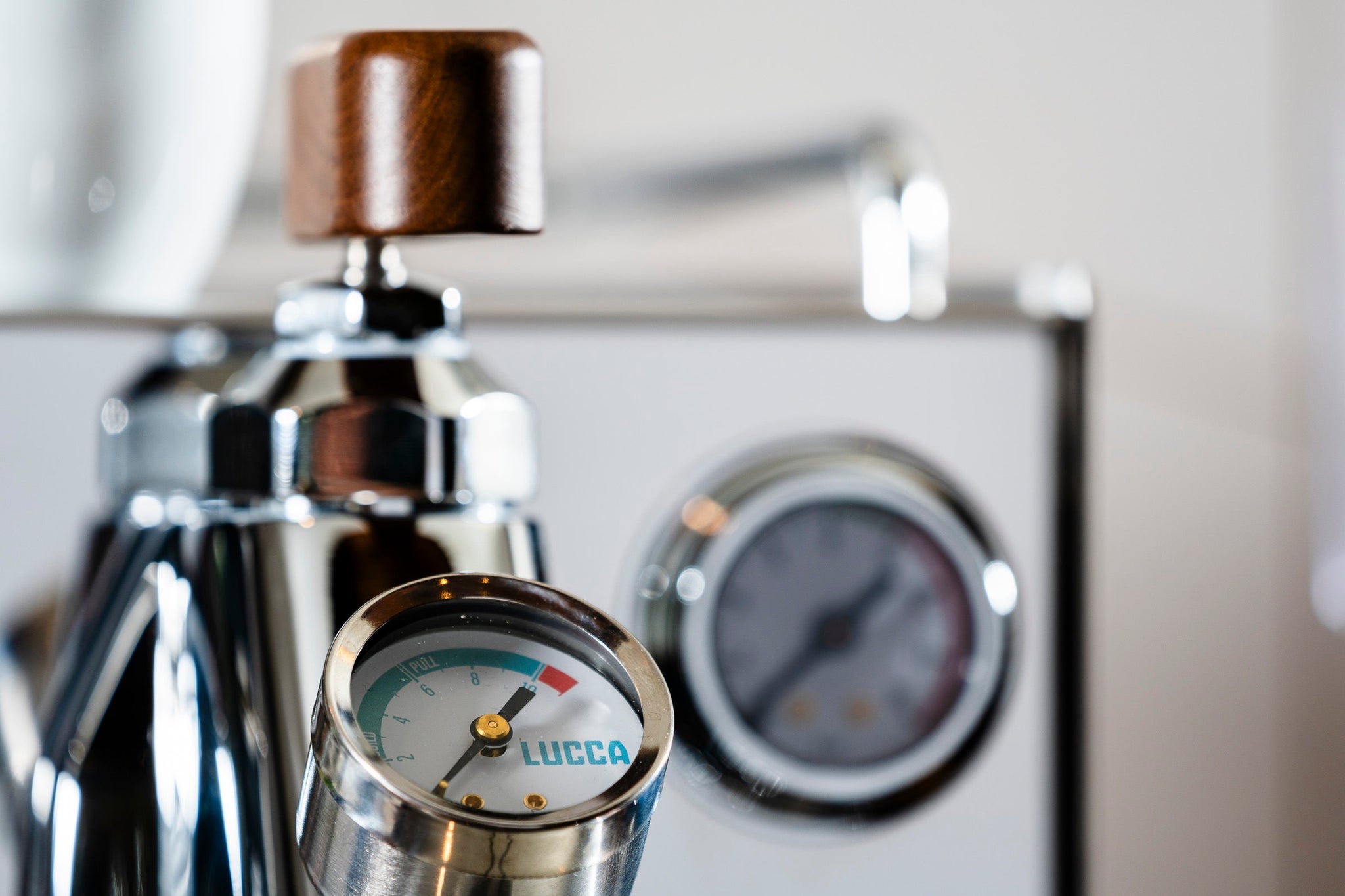 Close up of espresso machine front showing wooden knobs and chrome fittings