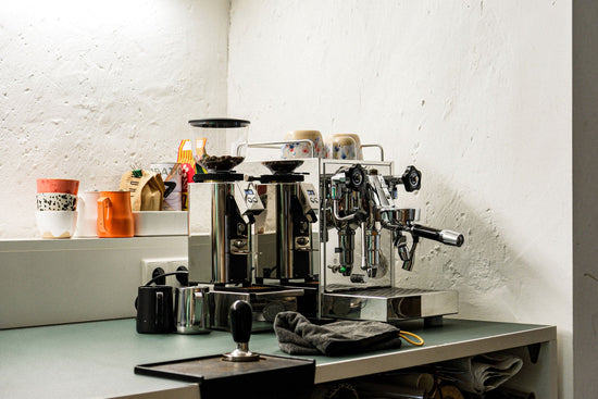 Espresso machines on a cafe counter with cups, bags of coffee, and accessories