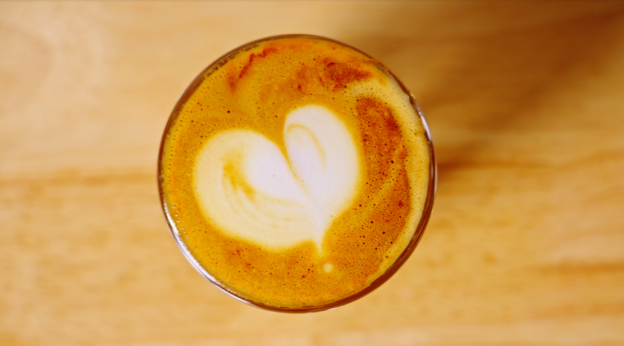 Top view of a latte with heart shaped art in a glass cup