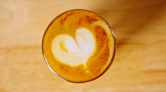 Top view of a latte with heart shaped art in a glass cup