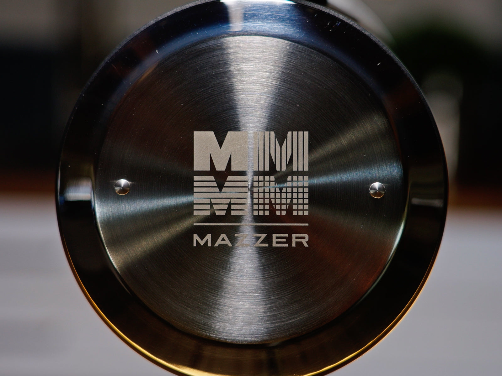 Close up of a polished Mazzer Mini espresso grinder lid with a brushed metal finish.