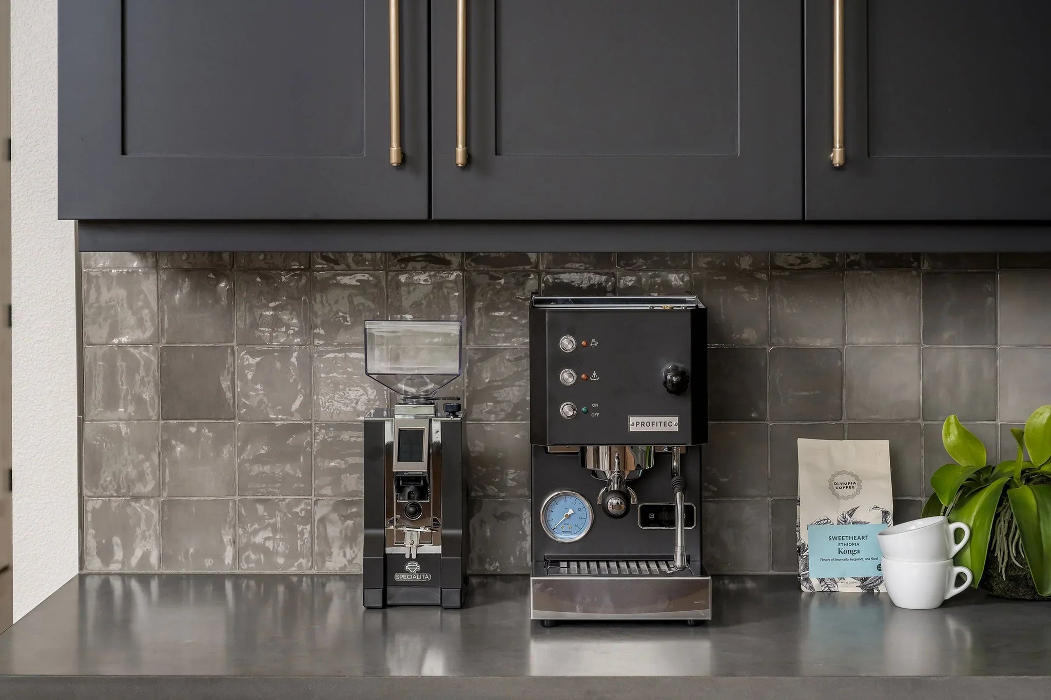 Modern espresso station with a black espresso machine and a grinder beneath dark upper cabinets