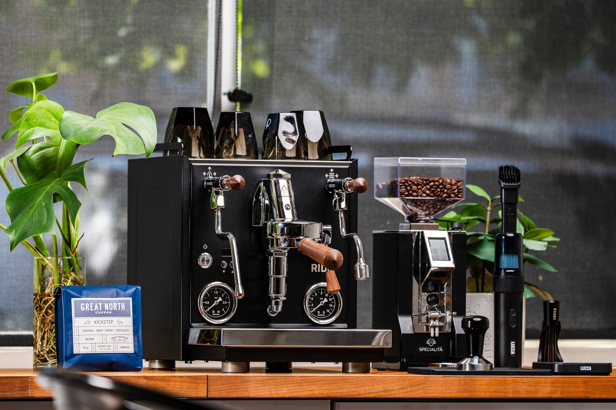 Profitec RIDE espresso machine with two group heads, wooden handles, cups on top, plant on the left