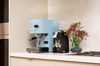 Blue Eureka Mignon Silenzio 55 grinder on a white kitchen counter beside a vase of pink flowers