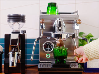 Front view of a chrome Profitec JUMP espresso machine with wooden portafilter handles and a green glass on top