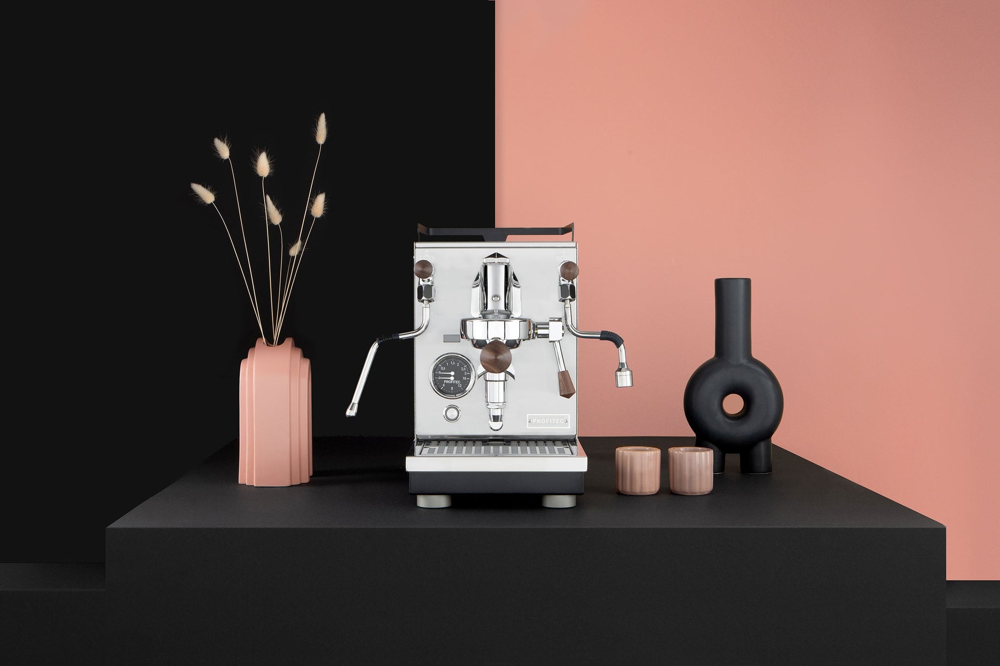 Profitec Jump espresso machine with flow control, chrome and wood finish on a black pink backdrop.