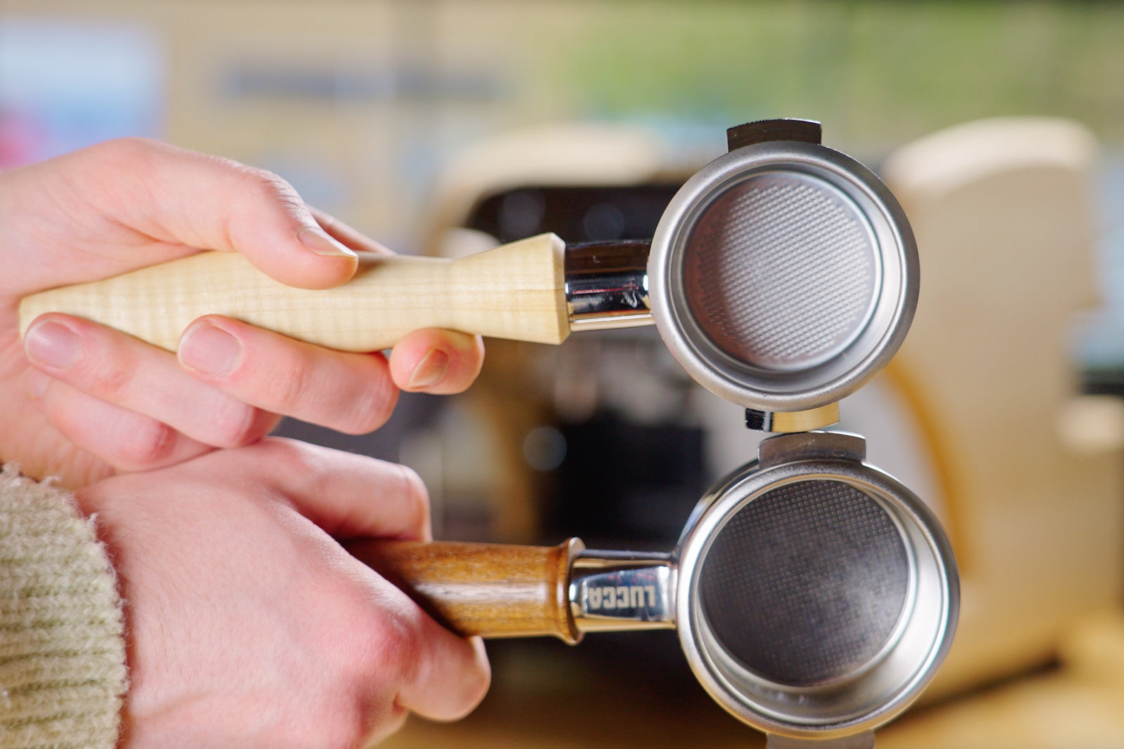 Close up of a hand gripping a wooden tamper over a dual basket portafilter.
