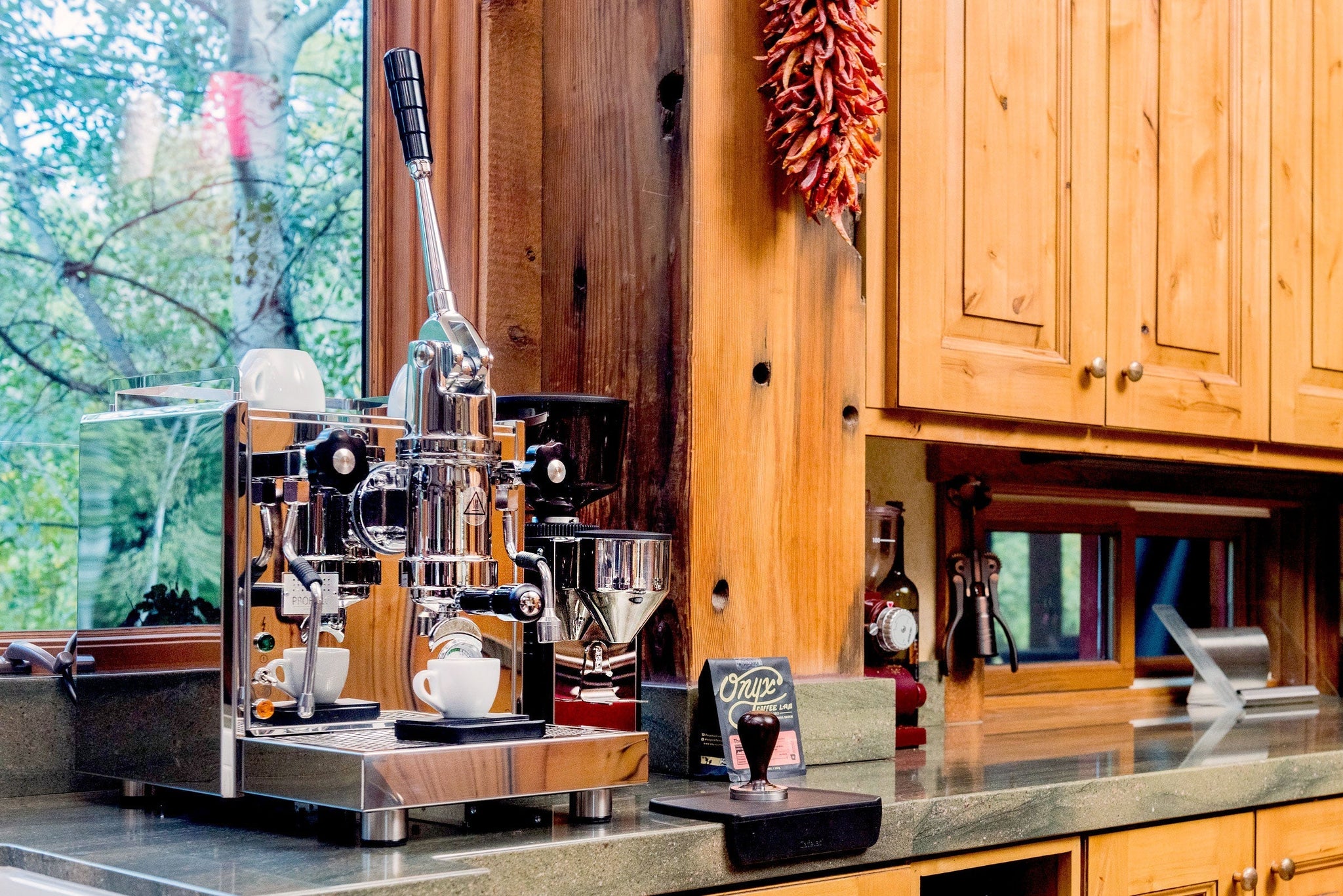 Classic manual lever espresso machine on a wooden counter with a tall chrome lever and black handle.