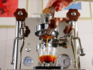 Espresso machine dispensing coffee into a glass with crema
