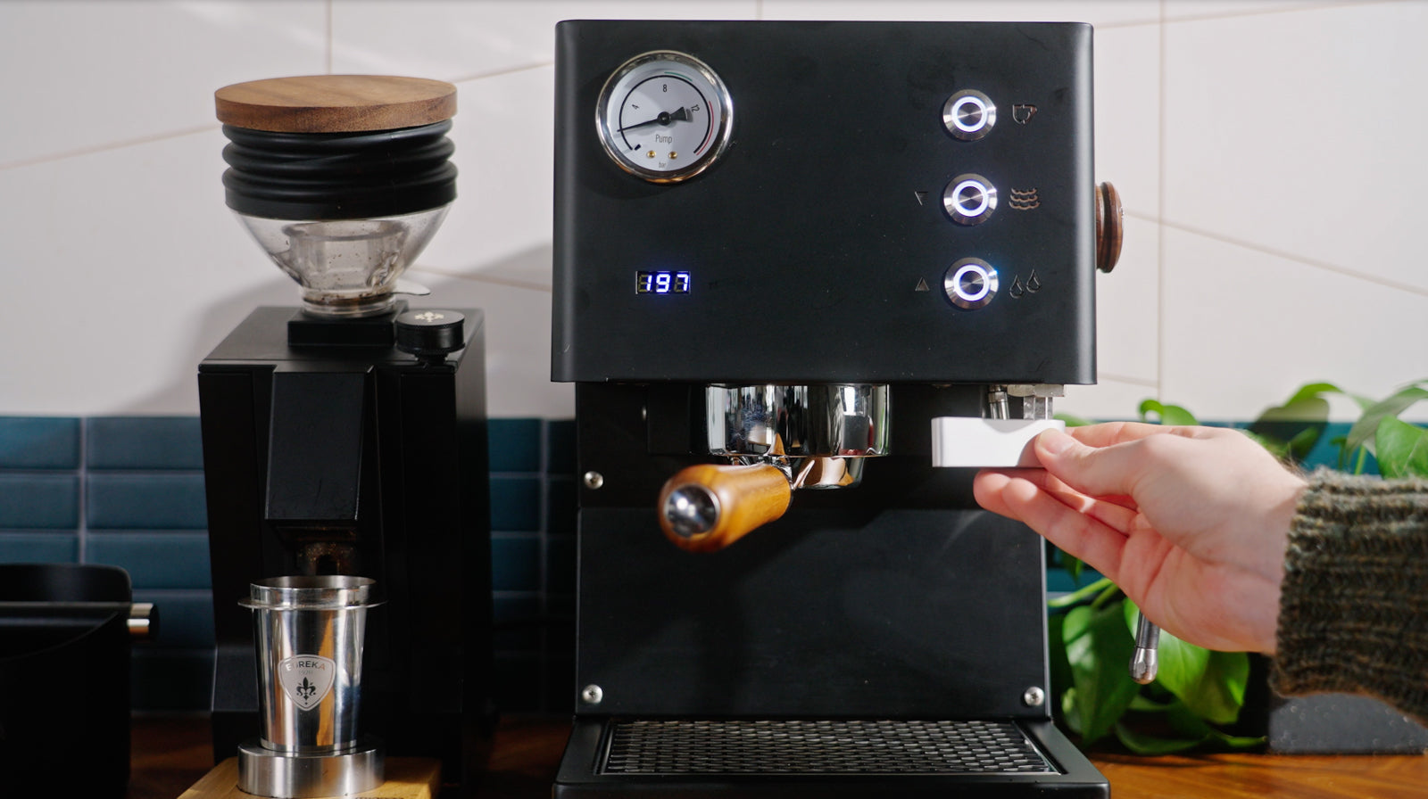 Person inserts a portafilter into a black LUCCA Tempo espresso machine in a cozy kitchen.