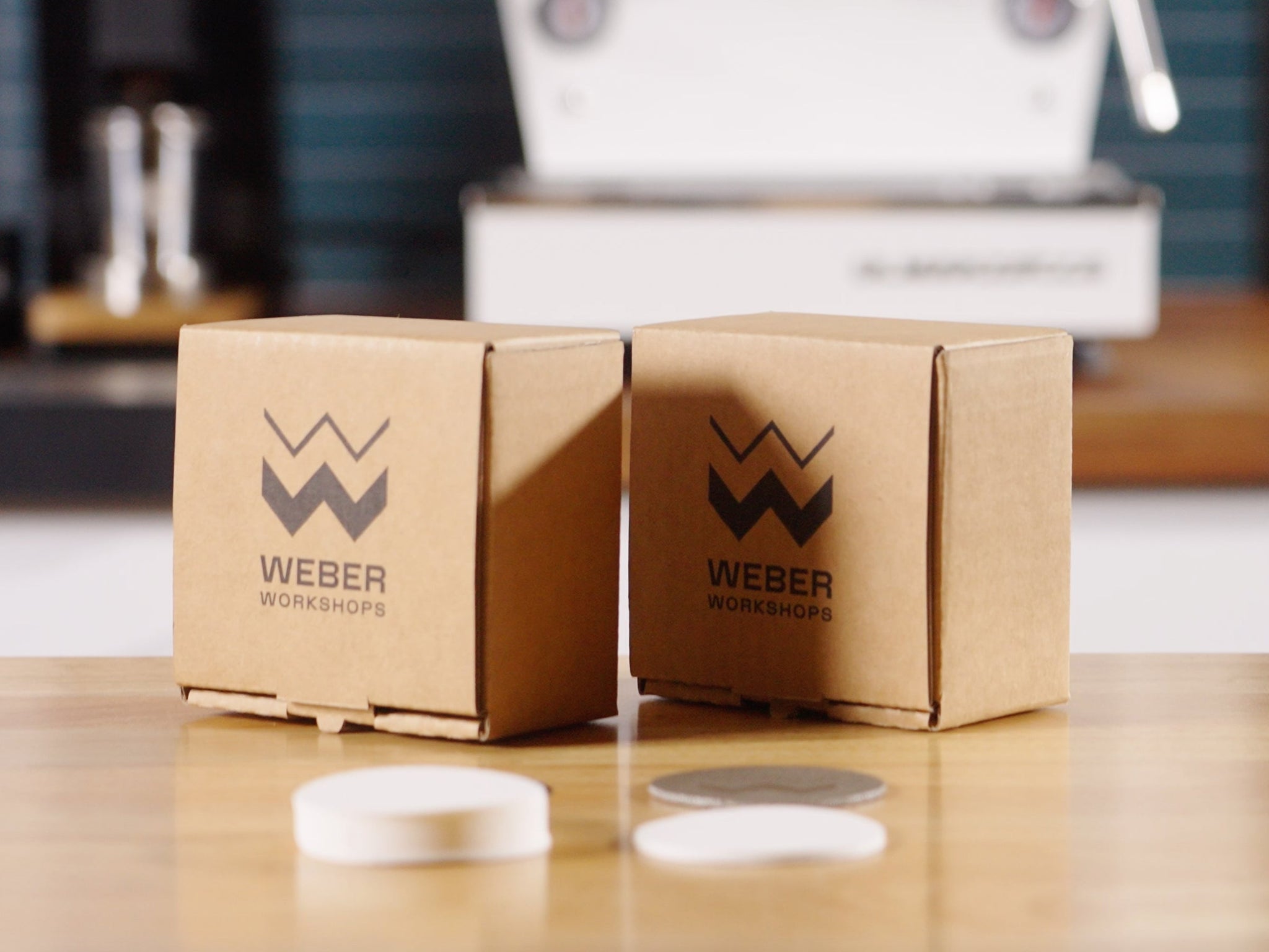 Two Weber Workshops boxes on a wooden table with round coffee filters arranged in front