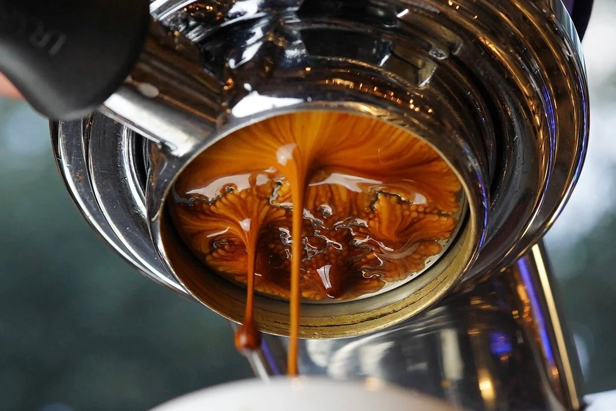 Close up of espresso extraction with crema swirling from the portafilter