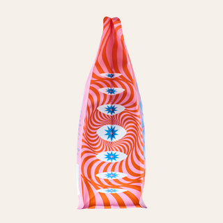 Top portion of a pink and orange swirl patterned Goshen Founders coffee bag with blue star logos against a pale background