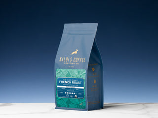 Standing Kaldi's Coffee Fair Trade Organic French Roast bag with green leaf panel against a blue backdrop