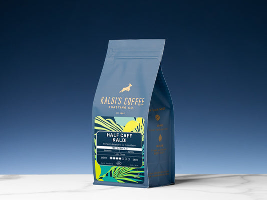 Kaldi's Coffee Half Caff bag on a display against a clear blue sky with colorful label art.