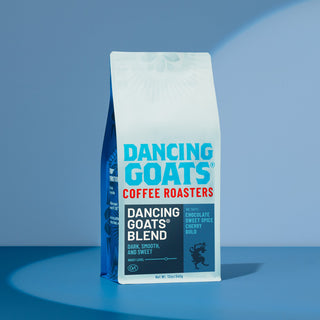 Dancing Goats Blend coffee bag standing upright with bold white and blue branding against a blue sky