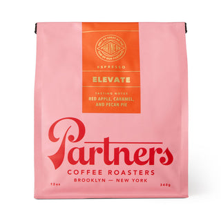 Pink Elevate coffee bag from Partners Coffee Roasters with an orange tasting notes panel listing red apple caramel and pecan pie.