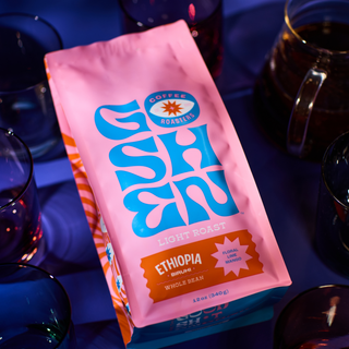 Pink Ethiopia Biruhi coffee bag by Goshen Roasters with blue logo and abstract design.