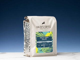 Half Caff Kaldi coffee bag from Kaldi's Coffee Roasting Co on a white surface with a dark blue backdrop.