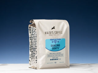 Kaldi's Dancing Goats blend bag against a deep blue sky with white packaging and goat logo.