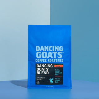 Close-up of Dancing Goats coffee bag showing white top and bold blue label against a blue background