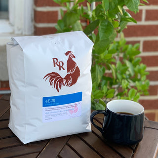 White Red Rooster Coffee bag with a red rooster logo and blue 4&20 French Roast label on a wooden table.