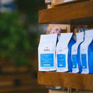 Zoka Fitzroy's coffee bags on a wooden shelf with a jar of iced coffee beside them