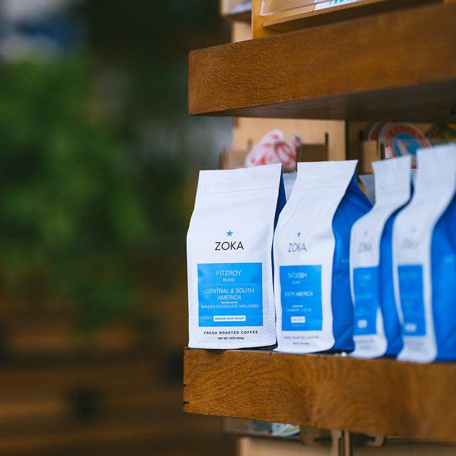 Zoka Fitzroy's coffee bags on a wooden shelf with a jar of iced coffee beside them